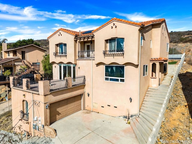 mediterranean / spanish-style home featuring a garage and a balcony