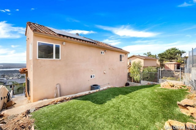 back of house featuring a yard and solar panels