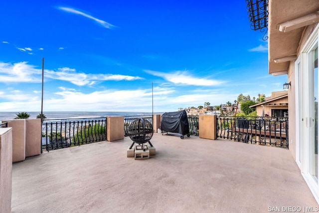 view of patio / terrace featuring grilling area, a balcony, and a water view