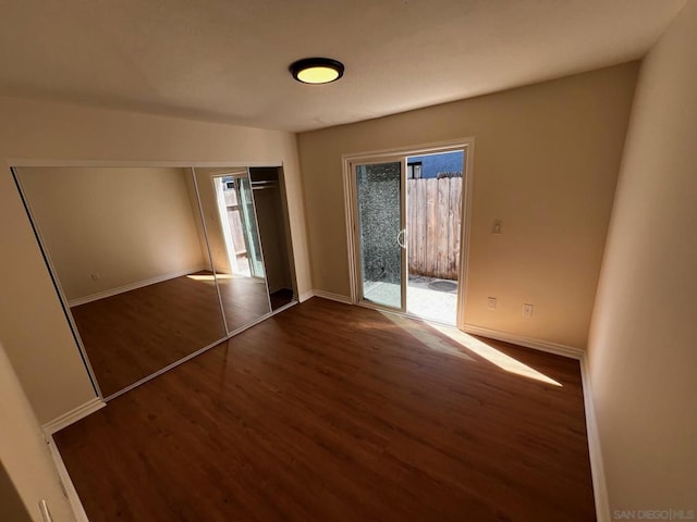 unfurnished bedroom featuring a closet, access to outside, and dark hardwood / wood-style floors