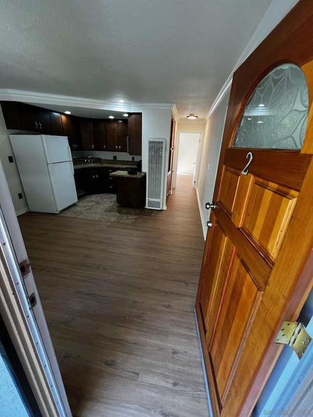 kitchen with white refrigerator, ornamental molding, light hardwood / wood-style floors, and dark brown cabinets