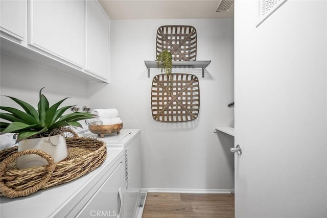 washroom featuring washer and clothes dryer, cabinets, and wood-type flooring