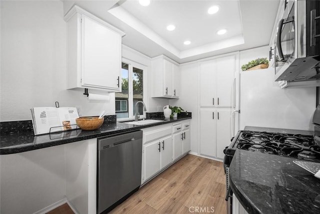 kitchen featuring a raised ceiling, sink, white cabinets, light hardwood / wood-style floors, and stainless steel appliances