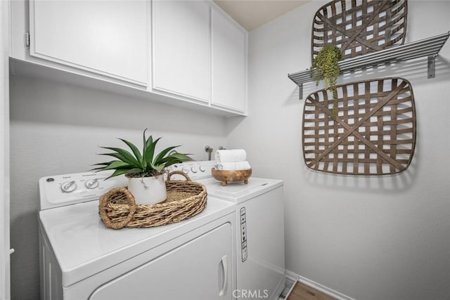 clothes washing area with cabinets and washer and clothes dryer