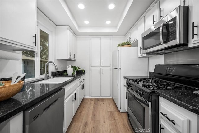 kitchen with appliances with stainless steel finishes, sink, dark stone counters, and white cabinets