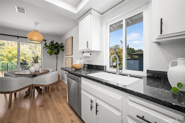 kitchen with sink, white cabinetry, decorative light fixtures, stainless steel dishwasher, and dark stone counters