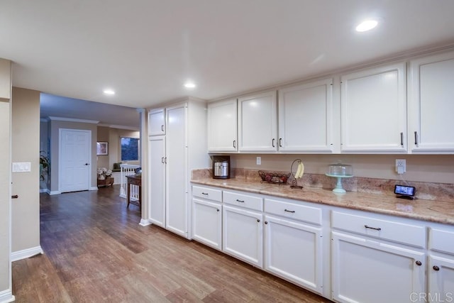 kitchen featuring white cabinetry, light stone counters, and hardwood / wood-style flooring