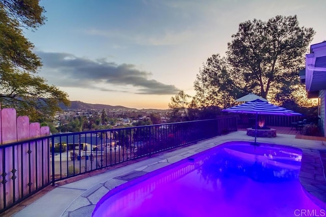 pool at dusk featuring a mountain view and a fire pit