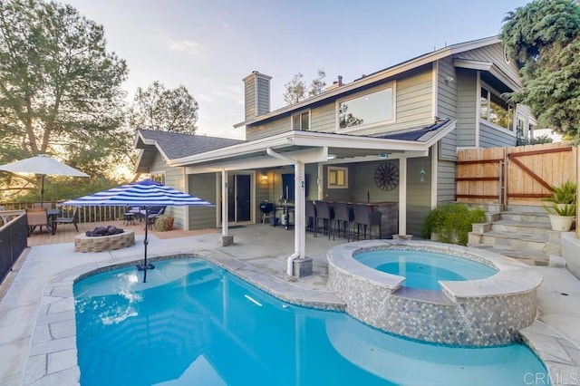 back of house with a patio, a fire pit, a pool with hot tub, and a bar