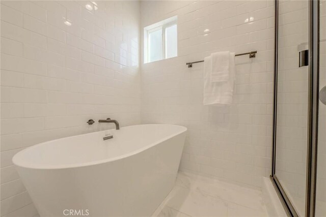 bathroom featuring independent shower and bath and tile walls