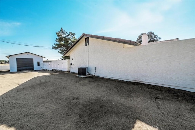 view of property exterior featuring central AC unit, a garage, and an outdoor structure