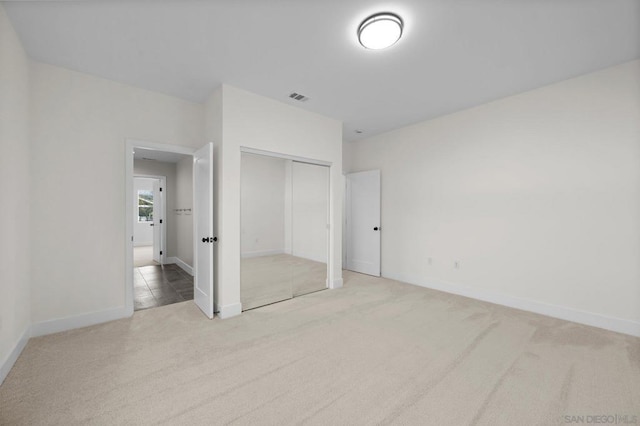 unfurnished bedroom featuring a closet and light carpet