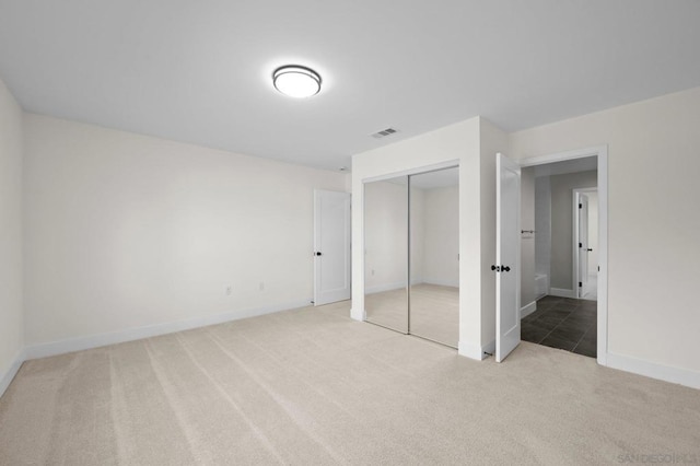 unfurnished bedroom with light colored carpet and a closet