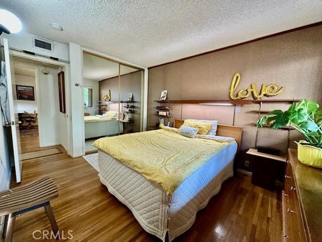 bedroom with hardwood / wood-style floors, a closet, and a textured ceiling