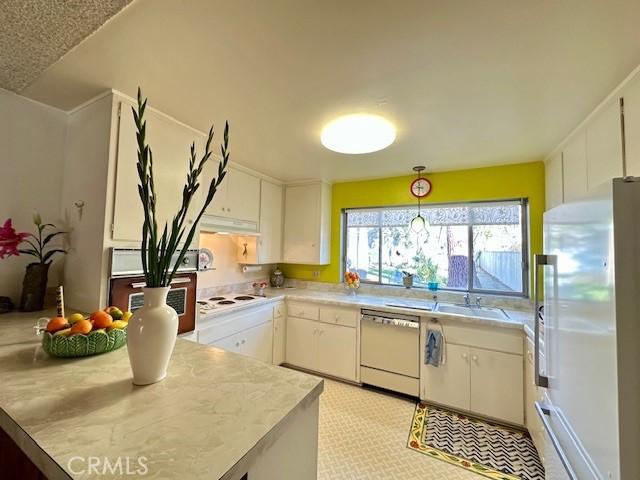 kitchen featuring white cabinetry, white appliances, and hanging light fixtures