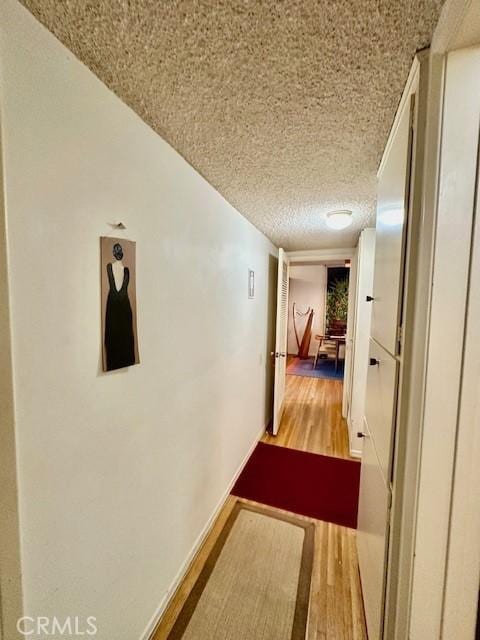 hall with wood-type flooring and a textured ceiling