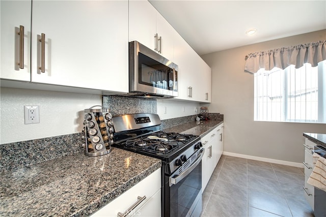 kitchen with white cabinetry, stainless steel appliances, light tile patterned floors, and dark stone counters