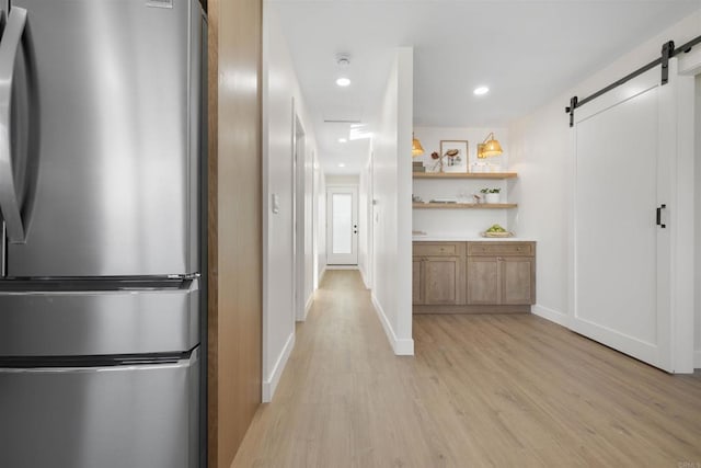 hallway with a barn door and light wood-type flooring