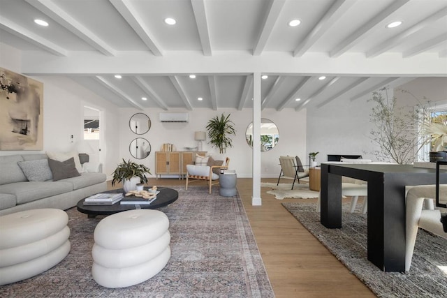 living room featuring beamed ceiling, hardwood / wood-style floors, and a wall unit AC