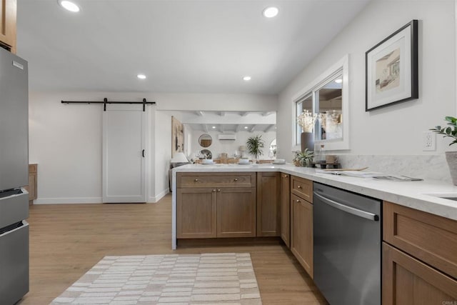 kitchen with stainless steel appliances, a barn door, and light hardwood / wood-style flooring