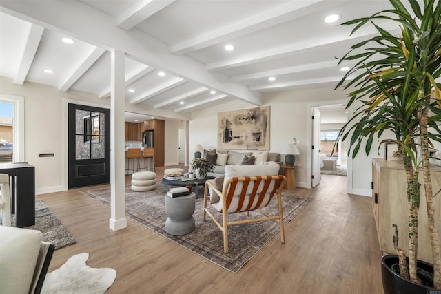 living room with plenty of natural light, lofted ceiling with beams, and light wood-type flooring