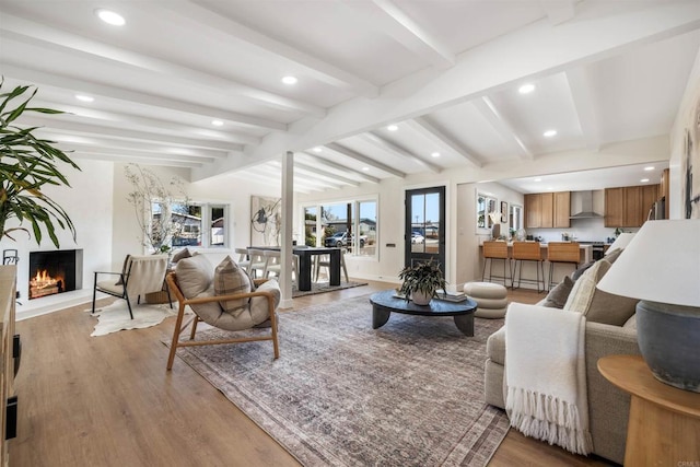 living room featuring lofted ceiling with beams and light hardwood / wood-style floors