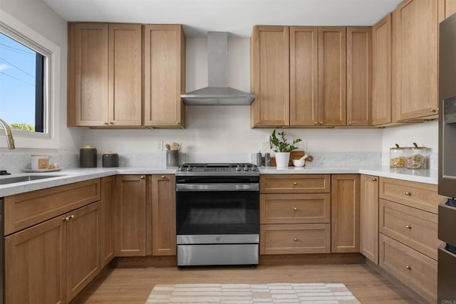 kitchen featuring light hardwood / wood-style flooring, sink, stainless steel range with gas cooktop, and wall chimney exhaust hood