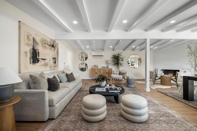 living room featuring hardwood / wood-style floors, beamed ceiling, and a wall mounted AC