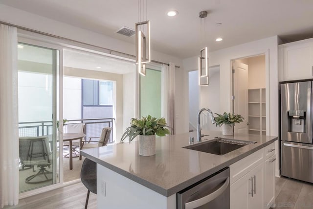 kitchen featuring pendant lighting, sink, white cabinets, dark stone counters, and stainless steel appliances