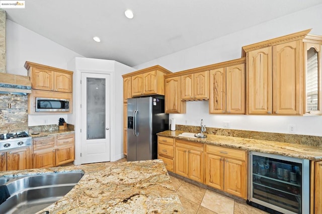 kitchen featuring light stone counters, sink, beverage cooler, and appliances with stainless steel finishes