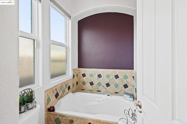 bathroom featuring toilet and tiled bath