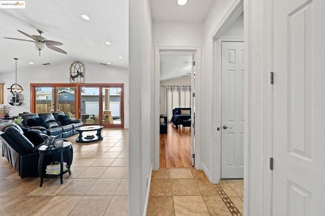 hallway with lofted ceiling and light tile patterned floors