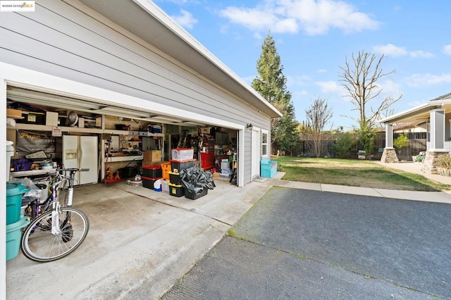 garage featuring a yard and white refrigerator with ice dispenser