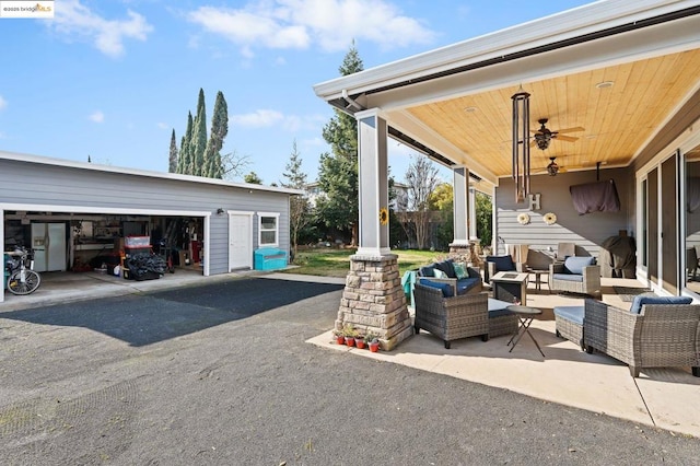 view of patio / terrace featuring an outdoor living space, an outdoor structure, a garage, and ceiling fan