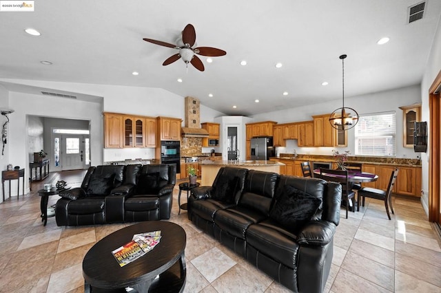 living room with vaulted ceiling, ceiling fan with notable chandelier, sink, and a wealth of natural light