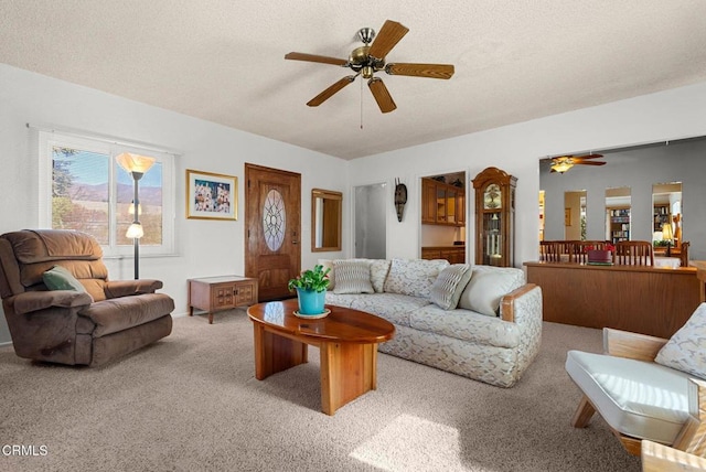 living room with ceiling fan, carpet flooring, and a textured ceiling