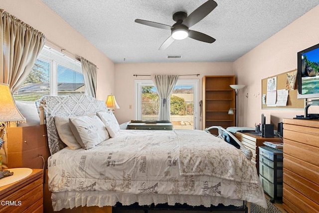 bedroom featuring multiple windows, ceiling fan, access to exterior, and a textured ceiling