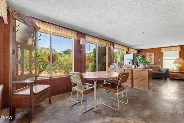 dining room featuring a textured ceiling and wood walls