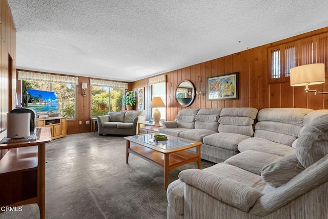 living room with wooden walls, concrete flooring, and a textured ceiling