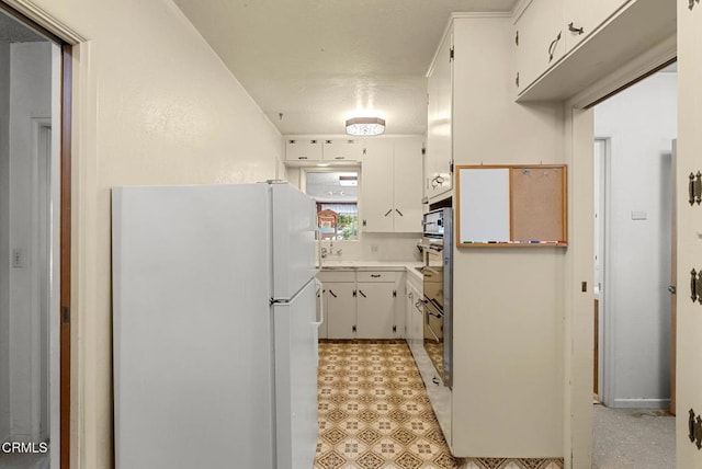 kitchen featuring light countertops, freestanding refrigerator, double oven, and white cabinetry