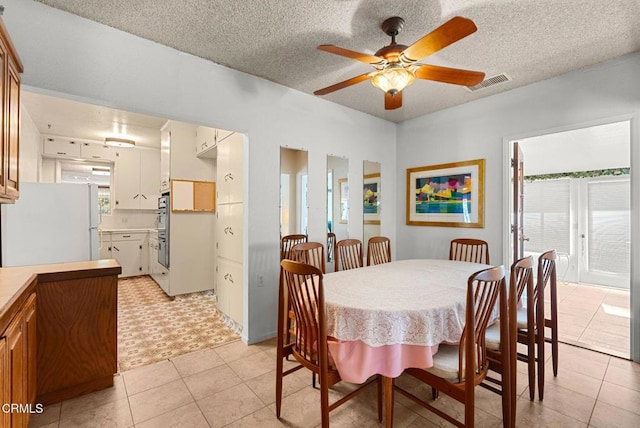 dining space with visible vents, a ceiling fan, a textured ceiling, and light tile patterned floors