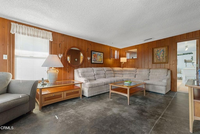 living room with visible vents, wood walls, and a textured ceiling