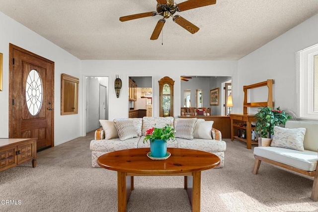 living room featuring a ceiling fan, a textured ceiling, and light colored carpet