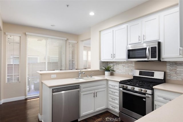 kitchen featuring sink, stainless steel appliances, tasteful backsplash, white cabinets, and kitchen peninsula