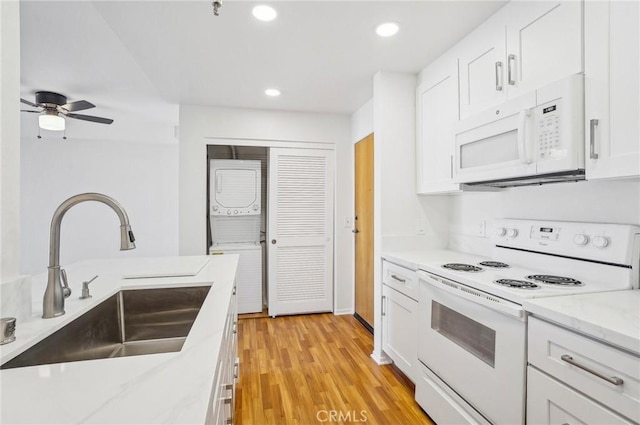 kitchen featuring light stone counters, sink, white appliances, and white cabinets