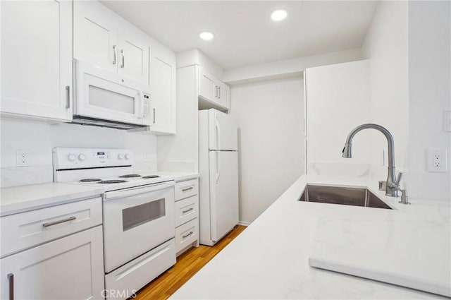 kitchen featuring sink, white appliances, light hardwood / wood-style flooring, and white cabinets