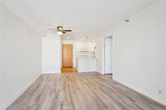 unfurnished living room with ceiling fan, sink, and light hardwood / wood-style floors