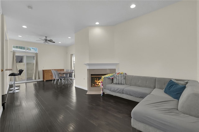 living room with ceiling fan, dark hardwood / wood-style floors, and a tiled fireplace