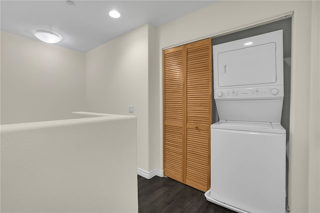 laundry room with dark wood-type flooring and stacked washer / drying machine