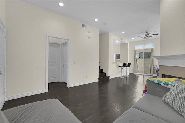 living room featuring dark wood-type flooring and ceiling fan